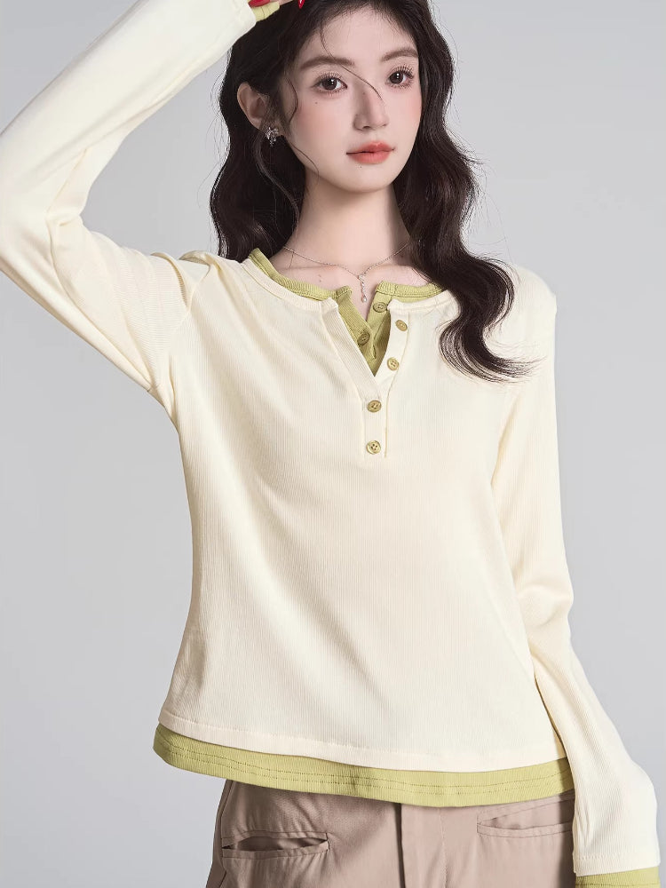 Woman wearing a cream long-sleeved shirt with green trim and buttons, paired with khaki pants.