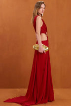 Side view of a woman showcasing the flowing silhouette and high slit of the red evening gown.