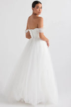 Back view of a model in a white off-the-shoulder wedding dress with a corset back and full tulle skirt.