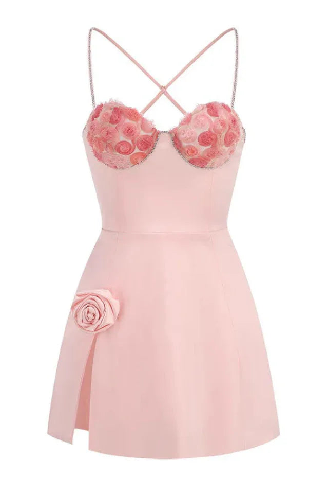A front view of a pink mini dress with a sweetheart neckline, floral applique, and a high slit.