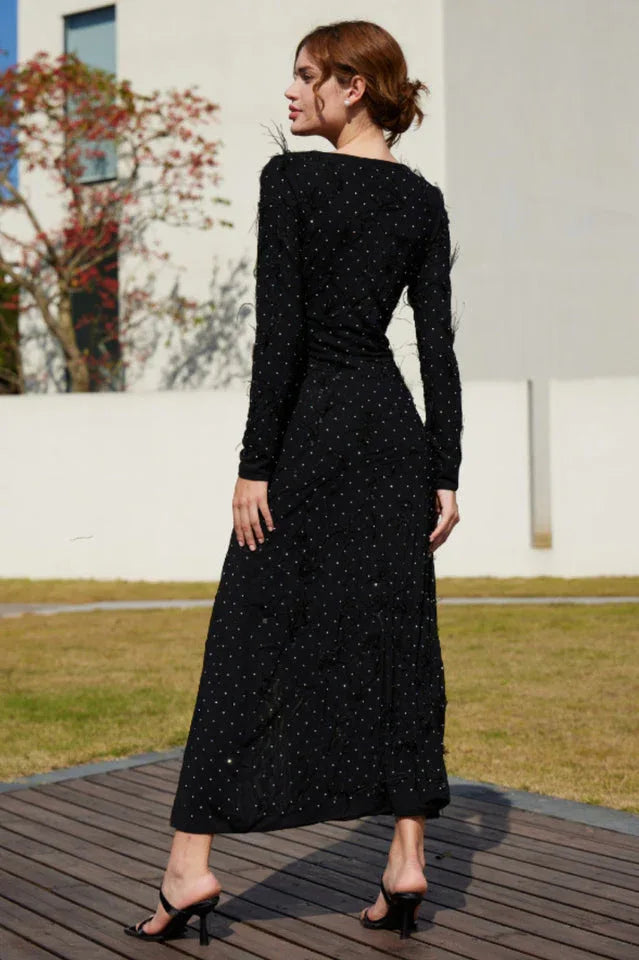 Close-up of the embellishments and feather trim on a black formal dress.