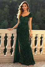 Woman wearing a floor-length emerald green sequined mermaid dress with a sweetheart neckline and a high slit, standing on a balcony.