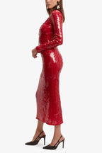 Woman wearing a long-sleeved, red sequined midi dress with a tie-front neckline, shown from the side.