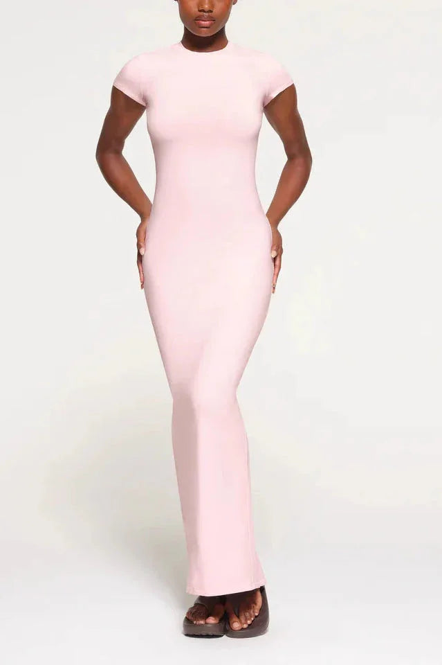 Woman wearing a light pink, full-length, fitted knit dress with cap sleeves and a round neckline.
