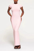 Woman wearing a light pink, full-length, fitted knit dress with cap sleeves and a round neckline.