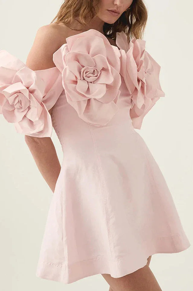 Close-up of the shoulder detail on a light pink off-the-shoulder mini dress featuring large floral appliques.