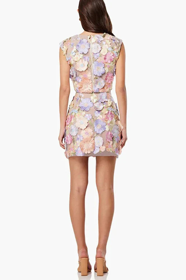 Back view of a woman wearing a floral applique crop top and mini skirt.