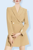 Model wearing a tan double-breasted blazer dress with cut-out details and embellished lapels.