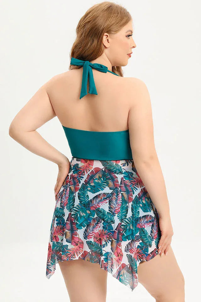 Back view of a plus-size women's teal halter neck swim dress with a tropical leaf print skirt Secondary image