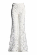 Close-up of white lace flare leg pants with floral embroidery.