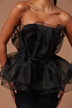 Close-up of the black ruffled peplum bodice of a formal gown.