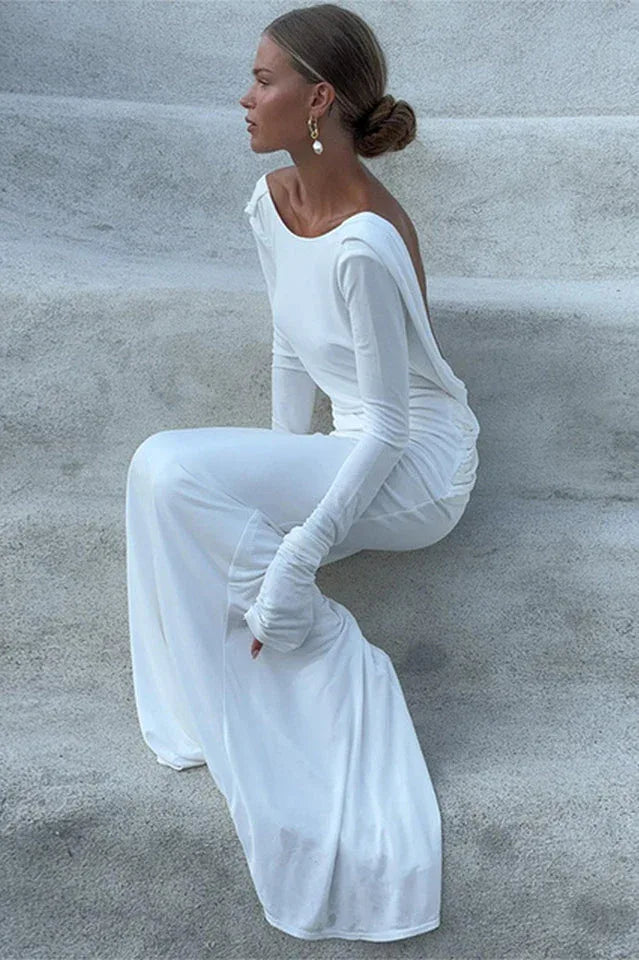 Woman in a white floor-length dress with long sleeves, sitting on steps.