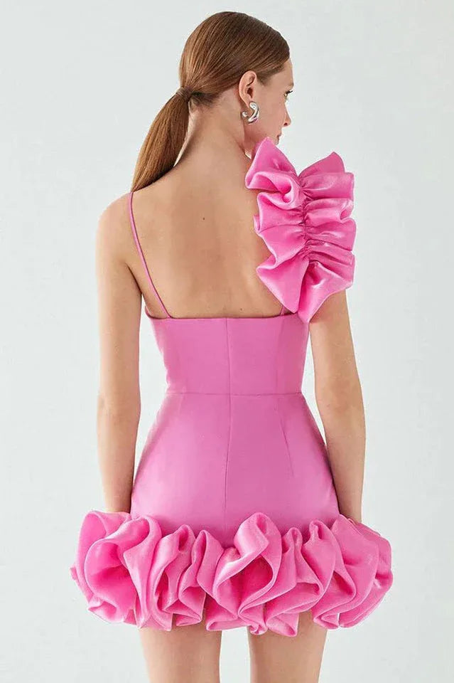 front view of a bright pink mini dress with a large ruffle on one shoulder and a ruffled hem