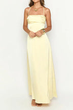 woman wearing a pale yellow satin maxi dress with spaghetti straps and a sweetheart neckline, hands clasped in front