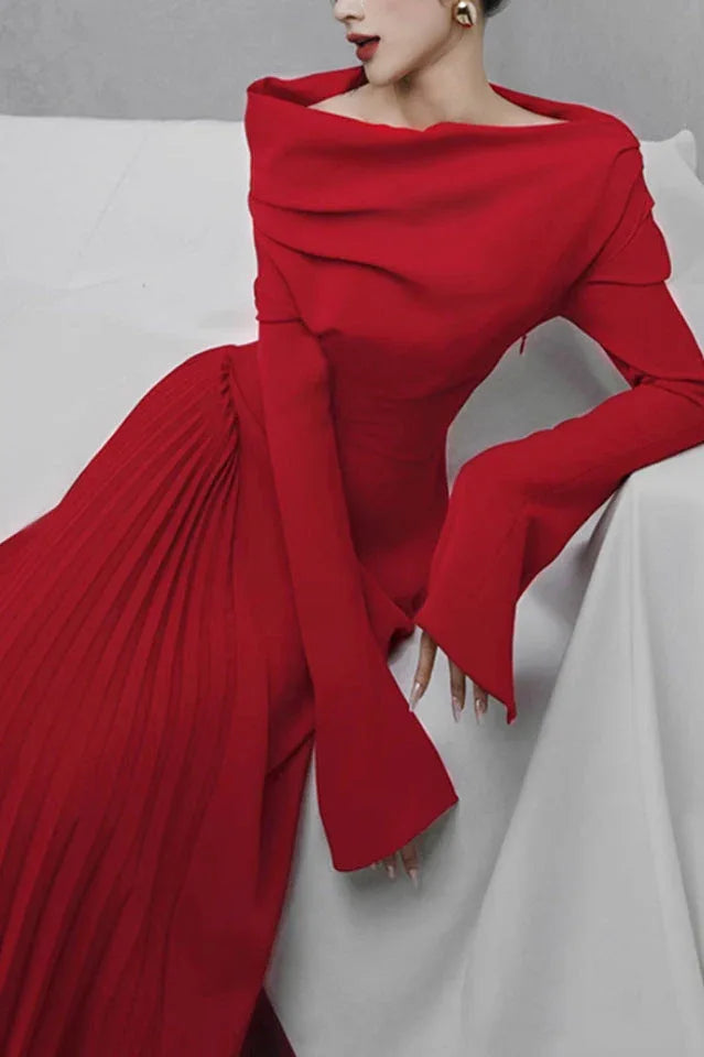 Close-up of a woman wearing a red off-the-shoulder dress, seated and leaning on a white surface.