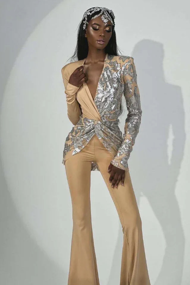 Close-up on the upper body of a woman in a designer jumpsuit, highlighting the sequined detailing and plunging neckline.