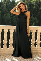 Woman adjusting her hair while wearing a black formal dress with a slit and halter neckline.