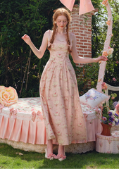 Woman wearing a pink floral print midi dress with ruffled straps in a garden setting