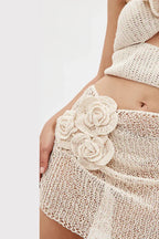 Close-up of floral appliqué on a cream crocheted mini skirt.