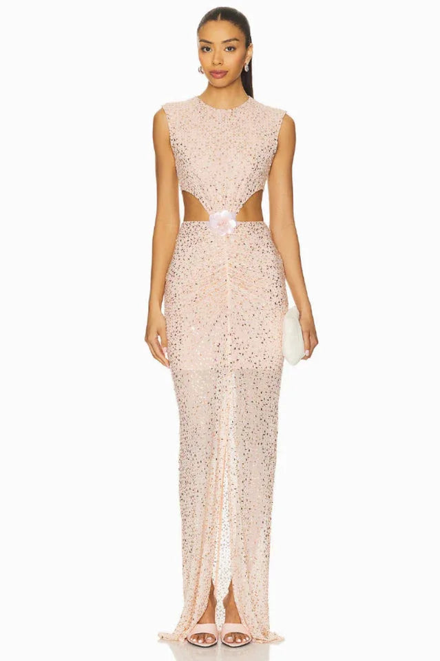 model wearing a long, sleeveless, blush pink sequined gown with cut-out details at the waist and a high slit