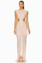model wearing a long, sleeveless, blush pink sequined gown with cut-out details at the waist and a high slit