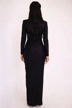 Back view of a woman wearing a black long-sleeved maxi dress.