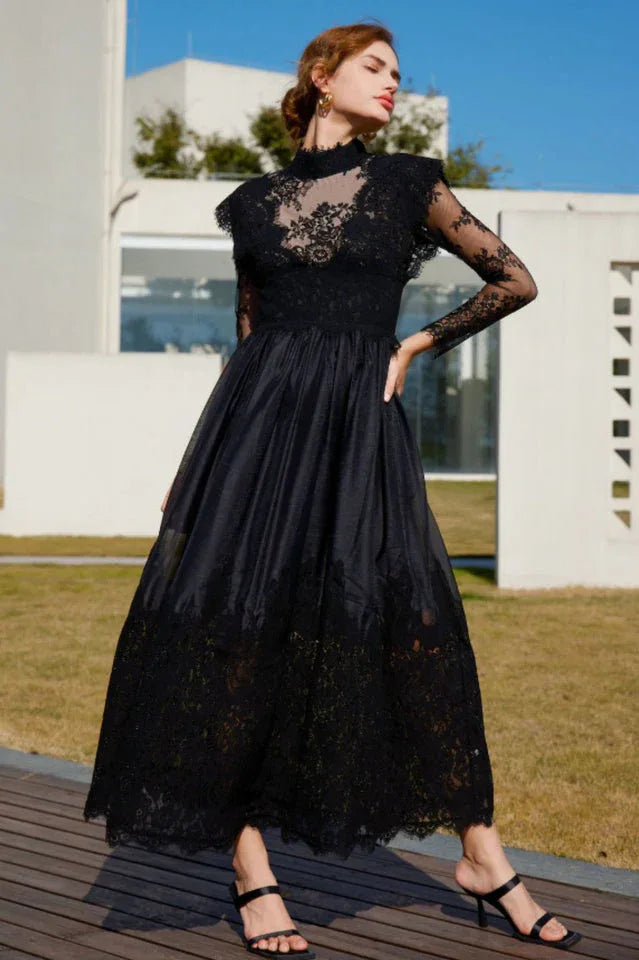 Close-up of a woman's face and upper body wearing a black lace and satin formal dress.