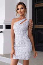 Woman in a sparkling white sequined one-shoulder dress with shoulder chain accents.