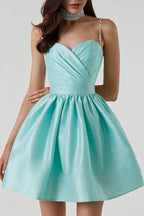 Close-up of the bodice and skirt of a short, aqua satin dress with a sweetheart neckline, ruched detailing, and embellished straps.