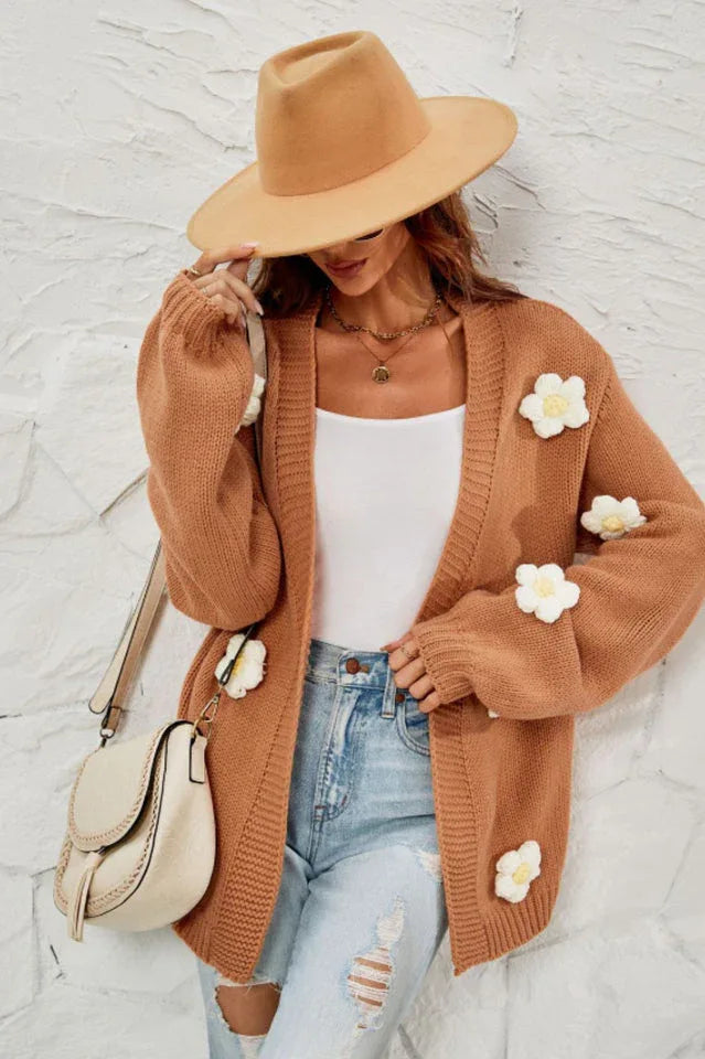Close-up of a woman wearing a brown floral cardigan, showing the texture of the knit and the detail of the floral embellishments.