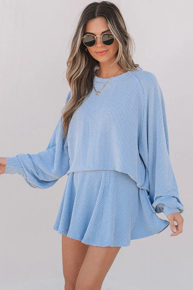 Front view of a woman in a blue striped two-piece set, showing the cropped top and skirted shorts. Secondary image