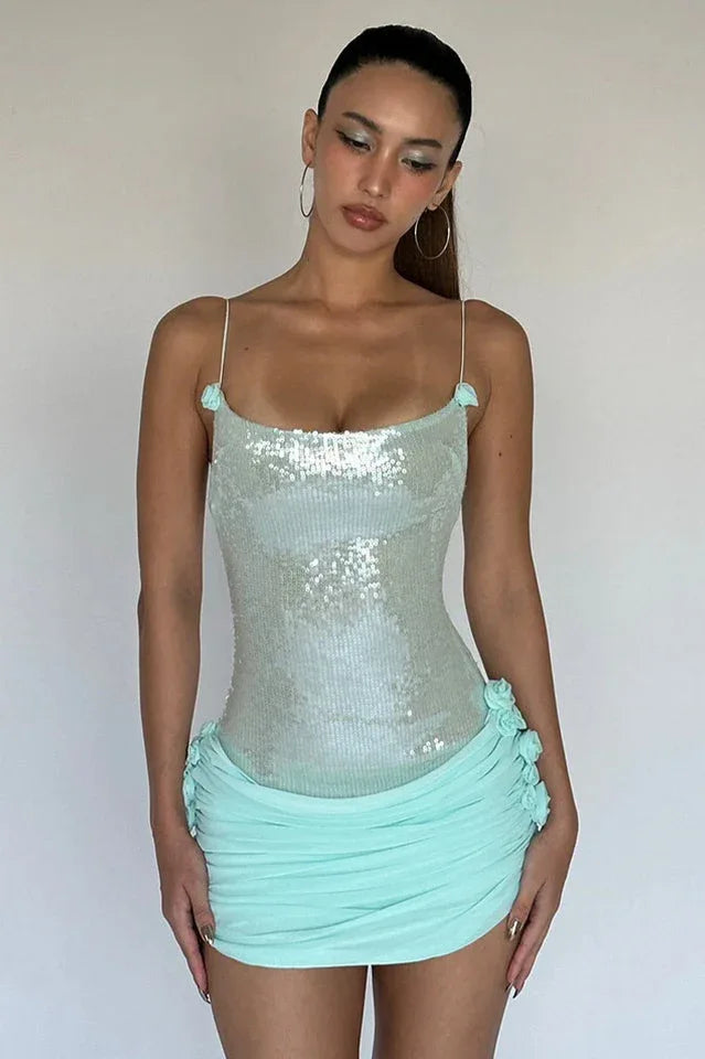 Close-up of a woman wearing a light blue sequined bodice dress with ruched detailing and floral appliques.
