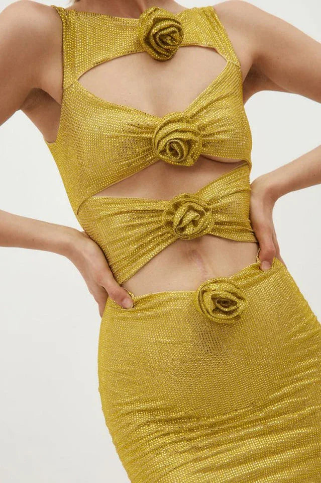 Detail shot of the bodice of a gold metallic knit mini dress with cut-out details and floral appliqués