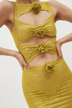 Detail shot of the bodice of a gold metallic knit mini dress with cut-out details and floral appliqués