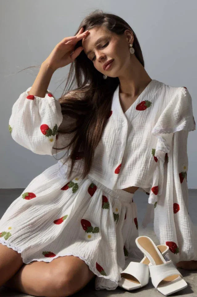 Woman wearing a white cropped blouse with strawberry print and ruffled sleeves, paired with a matching strawberry print skirt. Main image