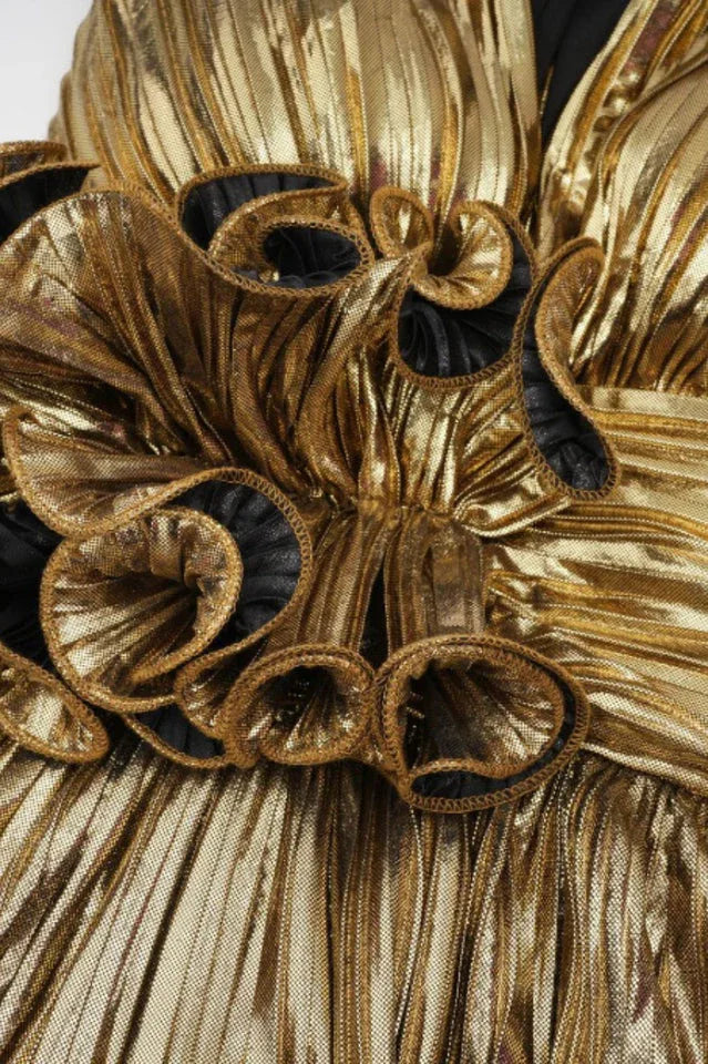 Close-up of the ruffled floral detail on the bust of a gold metallic tiered dress.