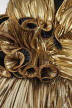 Close-up of the ruffled floral detail on the bust of a gold metallic tiered dress.