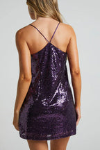 Back view of a woman in a purple sequin slip dress with criss-cross spaghetti straps.