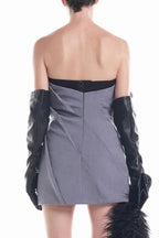 Back view of a model wearing a grey strapless dress with a rose bodice and black opera gloves.