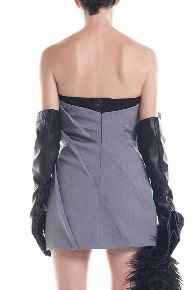 Back view of a model wearing a grey strapless dress with a rose bodice and black opera gloves.