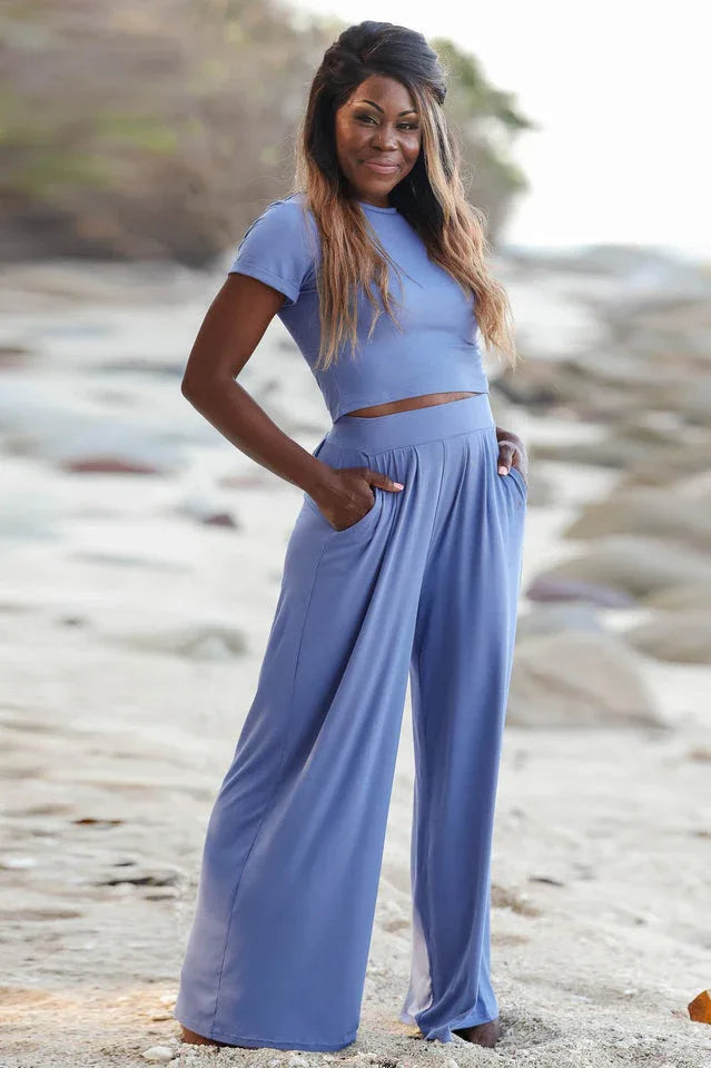 Woman wearing a blue crop top and wide leg pants on a beach