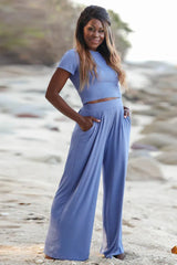 Woman wearing a blue crop top and wide leg pants on a beach
