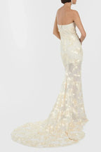 Rear view of a woman in a strapless ivory gown with gold floral embroidery and a train, showcasing the full length and train.
