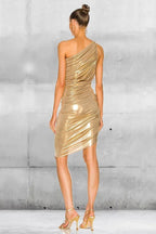 Woman wearing a gold one-shoulder ruched dress with an asymmetrical hemline, back view, showing the dress from the waist up.