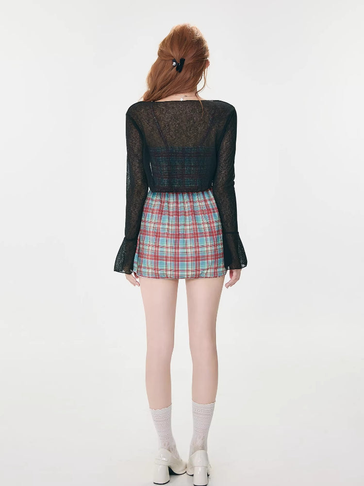 Back view of a woman wearing a plaid mini dress and a sheer black cardigan.