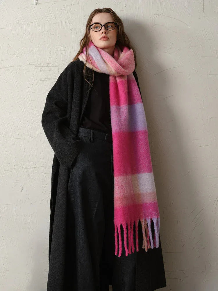 A woman poses with a vibrant, striped scarf draped over her dark outerwear.