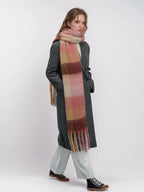 Model wearing a grey coat and pink plaid scarf