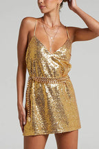 Woman wearing a gold sequin slip dress with a gold chain belt and layered necklaces.