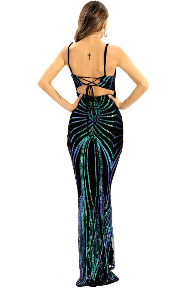 Back view of a woman wearing a black floor-length sequined gown with a geometric pattern in green and blue, showing an open back with lace-up detail.