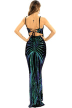 Back view of a woman wearing a black floor-length sequined gown with a geometric pattern in green and blue, showing an open back with lace-up detail.